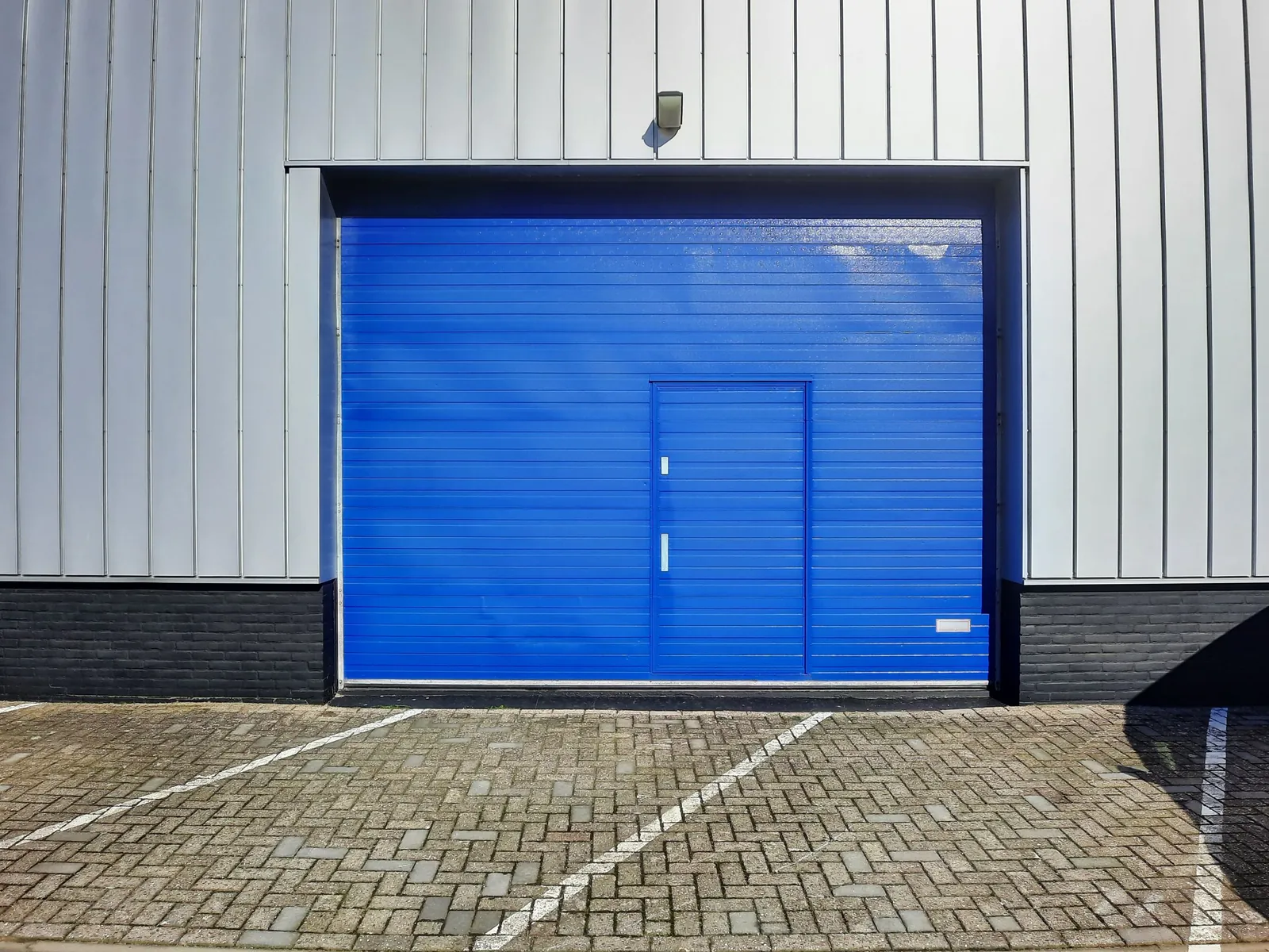 A modern industrial warehouse with a blue roll-up garage door